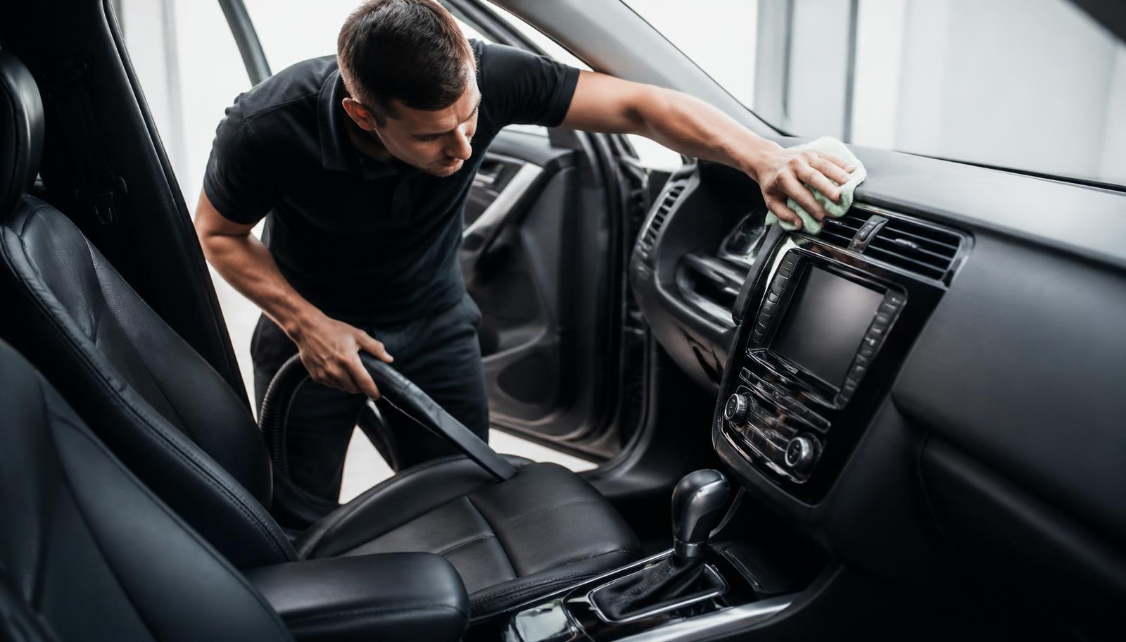 Technicus stofzuigt en poetst het interieur van een wagen