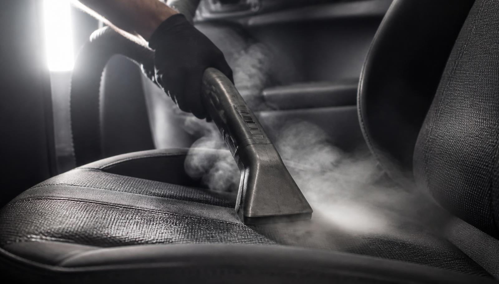 Stoomreiniger op een autozetel voor dieptereiniging van de bekleding